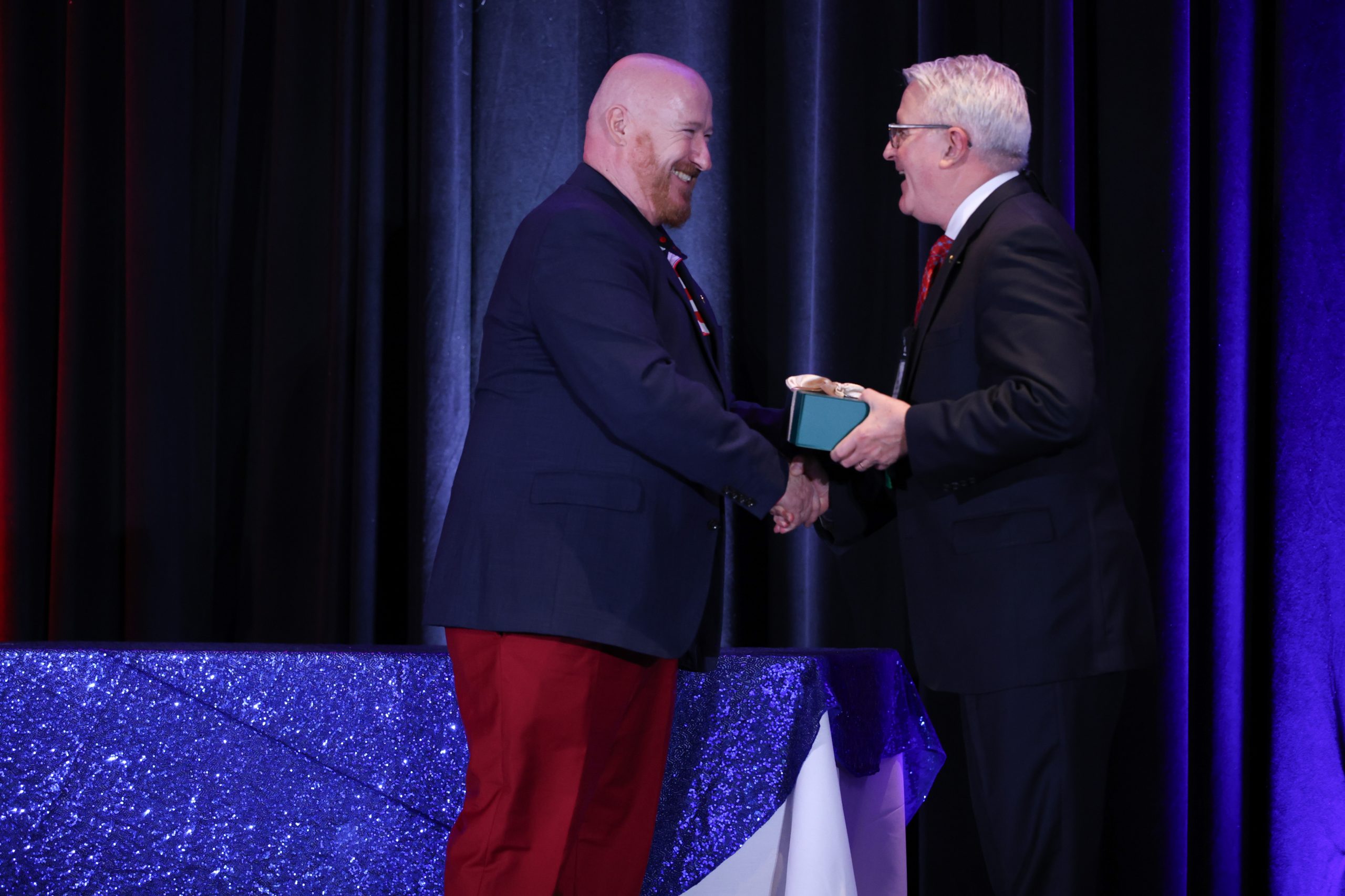 two men shaking hands on a stage