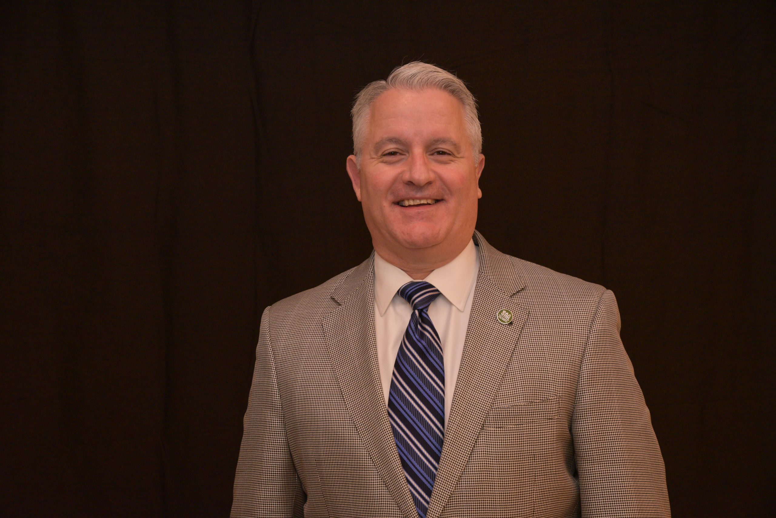 photo of a man standing in front of a black background, smiling