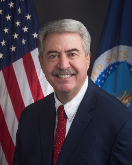 photo of a man smiling in front of an american flag